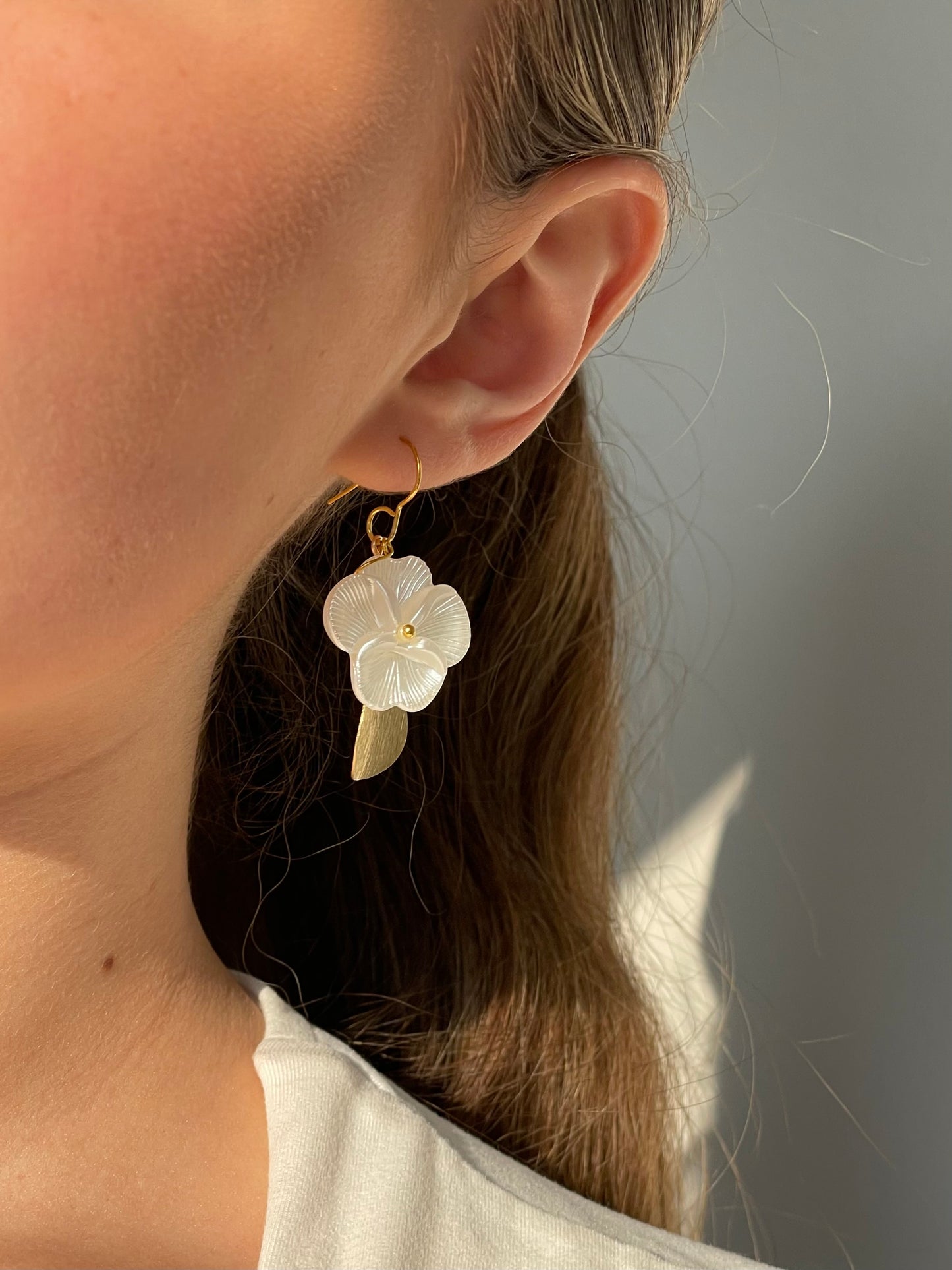 Close-up of a person wearing a floral earring with a neutral background